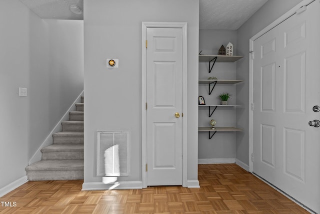 interior space with parquet floors and a textured ceiling