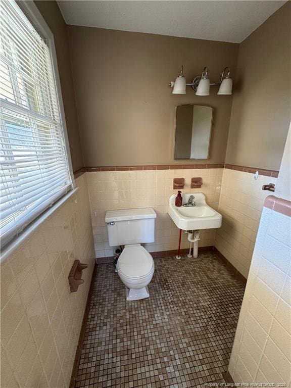 bathroom with toilet, tile patterned flooring, sink, and tile walls