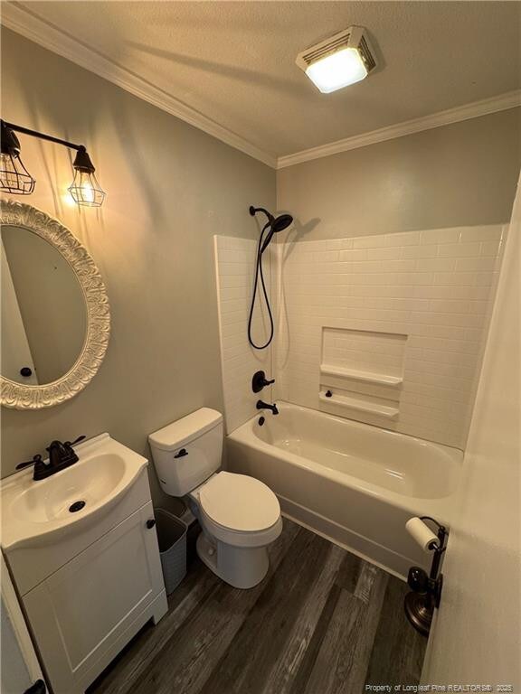 full bathroom with crown molding, wood-type flooring, shower / tub combination, and toilet