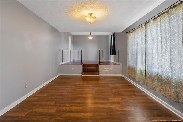 spare room featuring a textured ceiling and dark hardwood / wood-style flooring