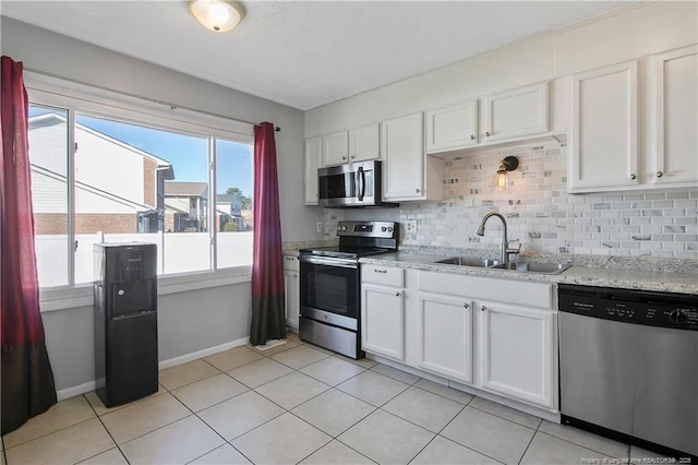 kitchen with tasteful backsplash, sink, white cabinets, and appliances with stainless steel finishes