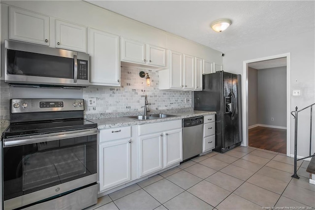 kitchen featuring sink, white cabinetry, stainless steel appliances, and light tile patterned floors