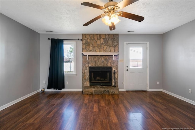 unfurnished living room with a textured ceiling, ceiling fan, a fireplace, and dark hardwood / wood-style floors