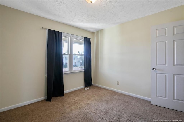 carpeted empty room with a textured ceiling