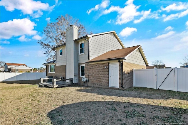 back of property with a deck and a lawn