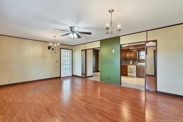 spare room featuring a textured ceiling, ceiling fan with notable chandelier, wood-type flooring, and crown molding