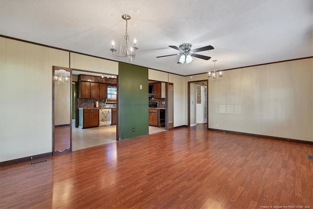 unfurnished living room featuring a textured ceiling, ceiling fan with notable chandelier, and crown molding