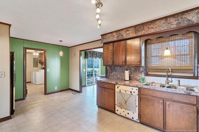 kitchen featuring ornamental molding, sink, washing machine and clothes dryer, dishwasher, and hanging light fixtures