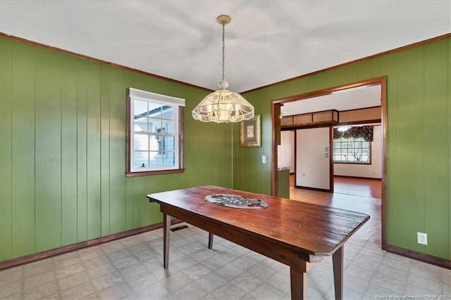 unfurnished dining area with ornamental molding and wood walls