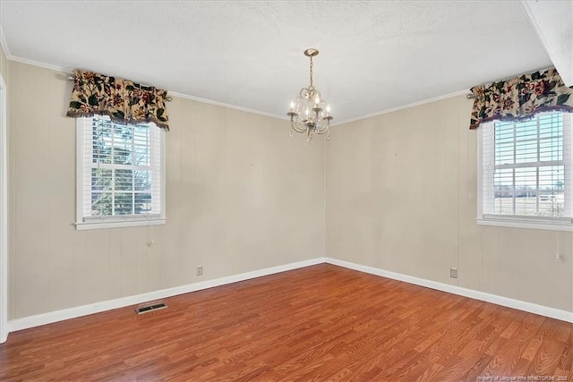 unfurnished room featuring a textured ceiling, wood-type flooring, crown molding, and a chandelier