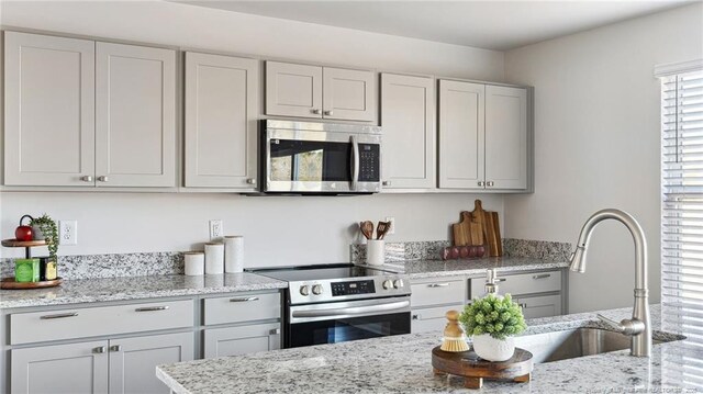 kitchen featuring light stone countertops, sink, and appliances with stainless steel finishes