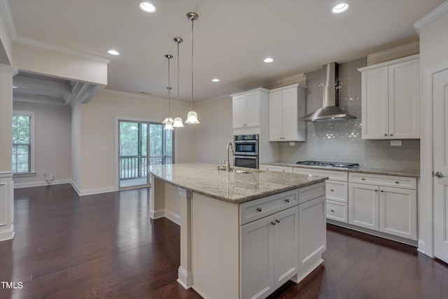 kitchen with a center island with sink, white cabinets, and wall chimney range hood