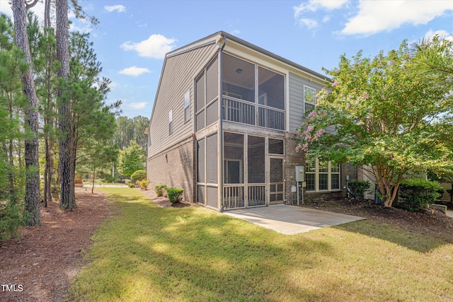 rear view of house featuring a patio, a sunroom, and a lawn