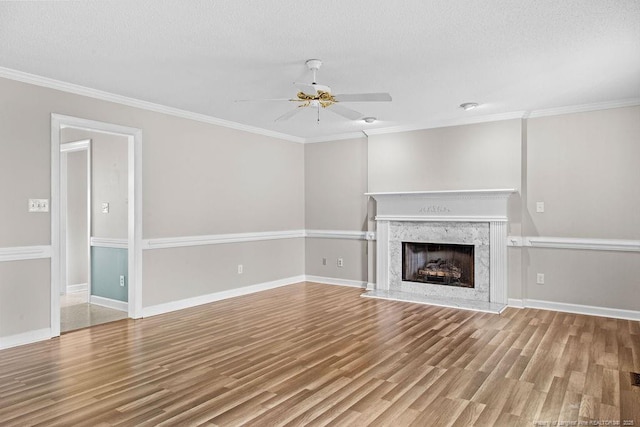 unfurnished living room with a high end fireplace, ornamental molding, a textured ceiling, ceiling fan, and hardwood / wood-style flooring