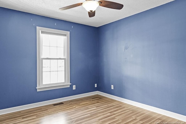 spare room with ceiling fan, a textured ceiling, and light wood-type flooring