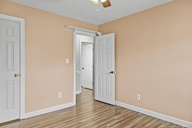 unfurnished bedroom featuring ceiling fan, light wood-type flooring, and a textured ceiling