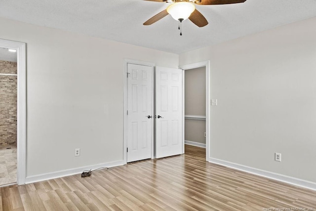 unfurnished bedroom featuring ceiling fan, ensuite bathroom, and light wood-type flooring