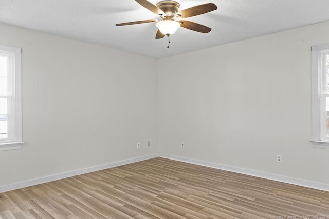 empty room with light hardwood / wood-style flooring, ceiling fan, and a healthy amount of sunlight