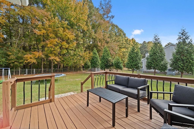 wooden terrace featuring an outdoor living space, a yard, and a trampoline