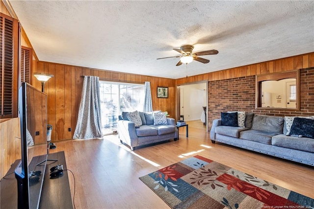 living room featuring ceiling fan, wood-type flooring, and wood walls