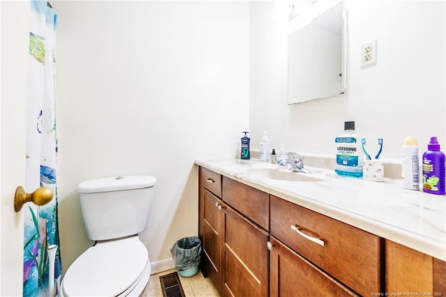 bathroom with toilet, vanity, and tile patterned floors