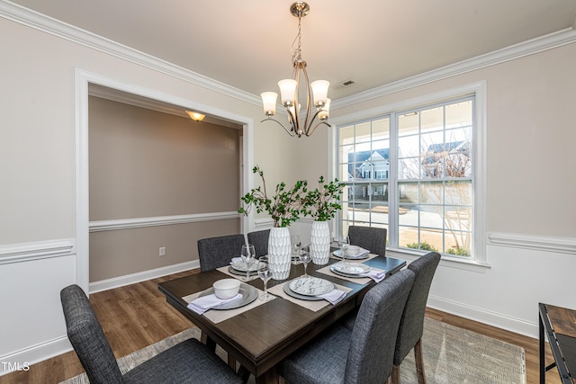 dining space with a chandelier, ornamental molding, and dark hardwood / wood-style floors