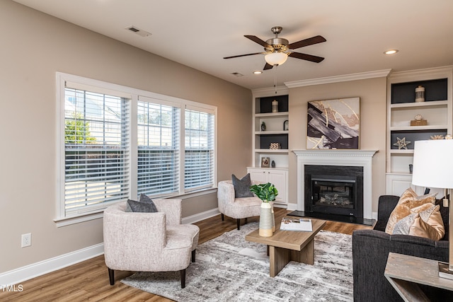 living room featuring ceiling fan, built in features, and hardwood / wood-style flooring