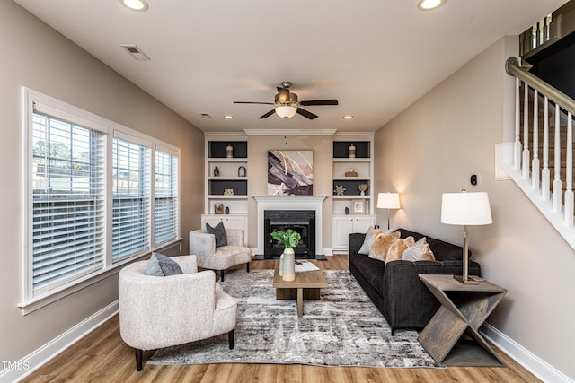 living room featuring ceiling fan, built in shelves, and hardwood / wood-style flooring