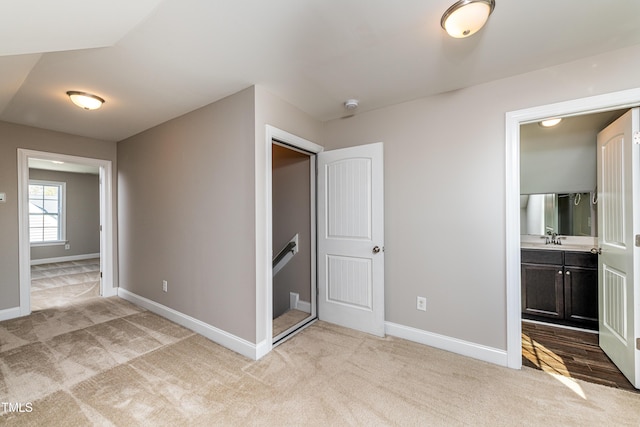 unfurnished bedroom featuring light carpet, sink, and connected bathroom