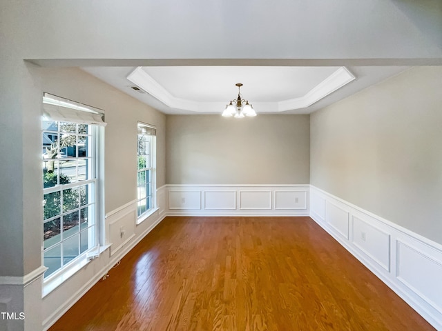 empty room featuring hardwood / wood-style flooring, a notable chandelier, and a tray ceiling