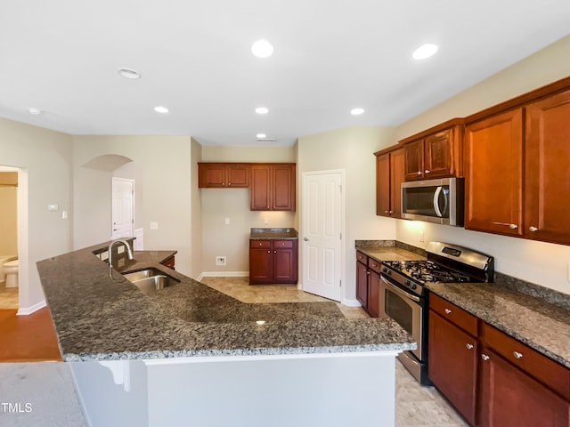1012 Fulbright Dr, Morrisville, NC 27560 - kitchen featuring stainless steel appliances, arched walkways, dark stone countertops, a center island with sink, and recessed lighting