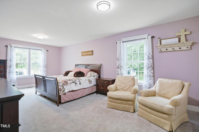 bedroom featuring light carpet, multiple windows, and baseboards