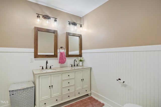 full bath featuring double vanity, wainscoting, and a sink