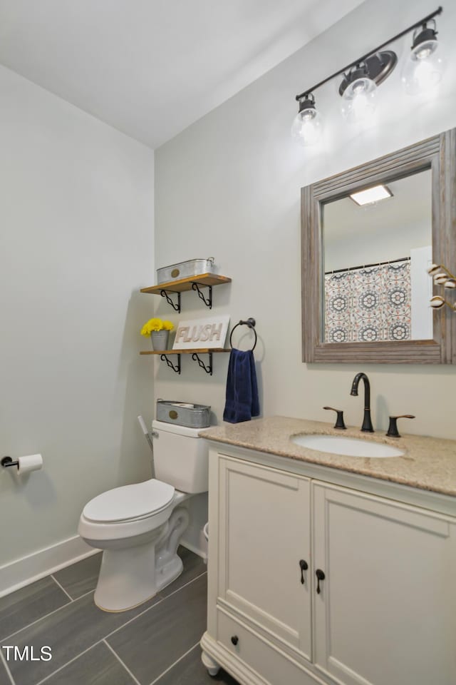 bathroom with toilet, vanity, and baseboards