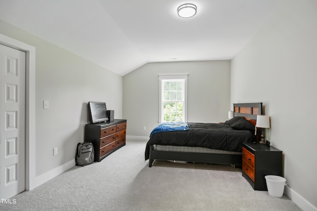 bedroom featuring lofted ceiling, light colored carpet, and baseboards