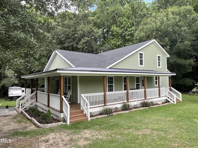 farmhouse featuring board and batten siding, a front yard, covered porch, and roof with shingles