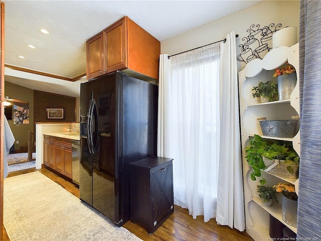 kitchen featuring black refrigerator with ice dispenser, stainless steel dishwasher, hardwood / wood-style floors, a textured ceiling, and vaulted ceiling