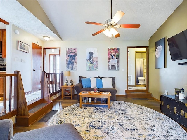 living area with dark hardwood / wood-style floors, ceiling fan, a textured ceiling, and vaulted ceiling