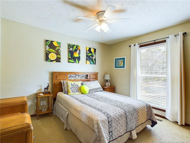 carpeted bedroom featuring multiple windows, ceiling fan, and a textured ceiling