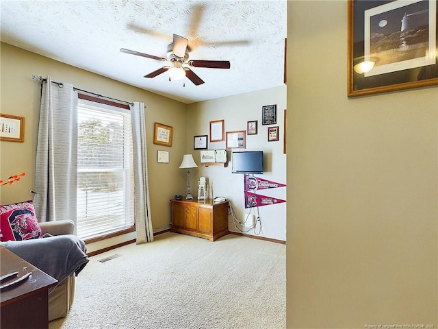 sitting room with light carpet, ceiling fan, and a textured ceiling