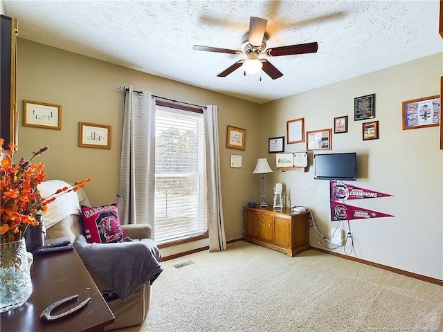 living area featuring light carpet, ceiling fan, and a textured ceiling