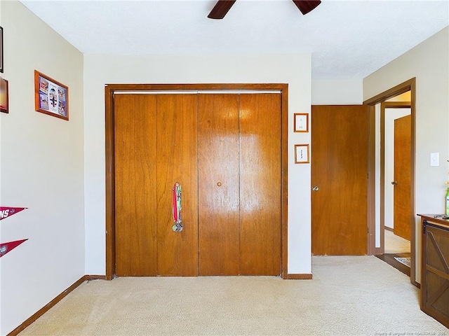 unfurnished bedroom with ceiling fan, light carpet, and a closet