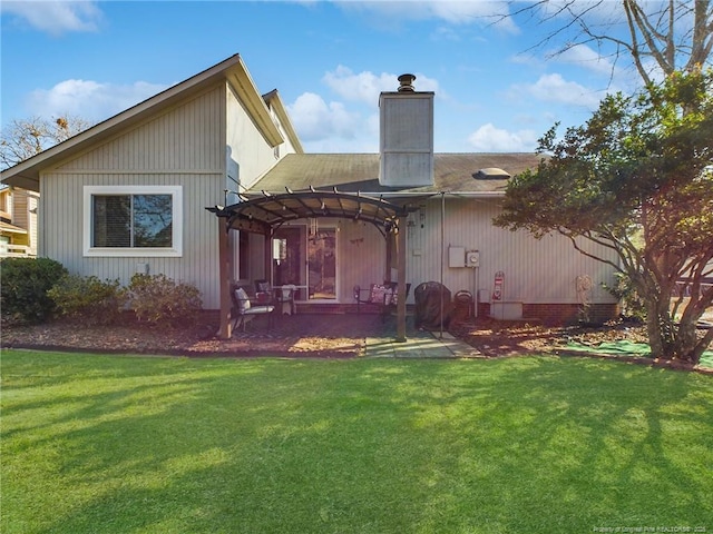 rear view of house featuring a pergola, a patio area, and a lawn