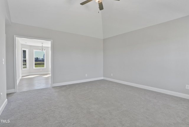 empty room with carpet, ceiling fan with notable chandelier, and baseboards