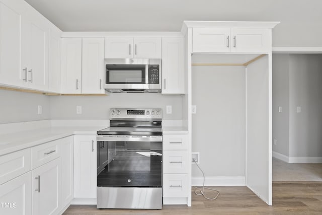 kitchen featuring light wood finished floors, appliances with stainless steel finishes, white cabinetry, and light countertops