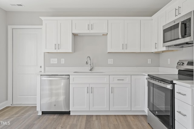 kitchen with visible vents, light countertops, light wood-style flooring, appliances with stainless steel finishes, and a sink