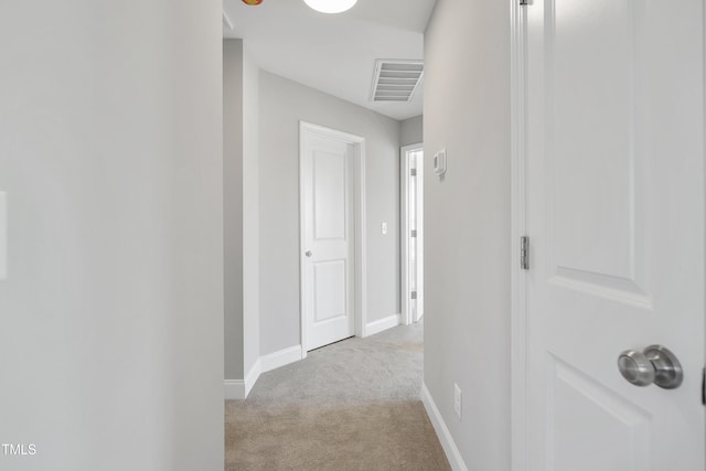 hallway with baseboards, visible vents, and carpet floors