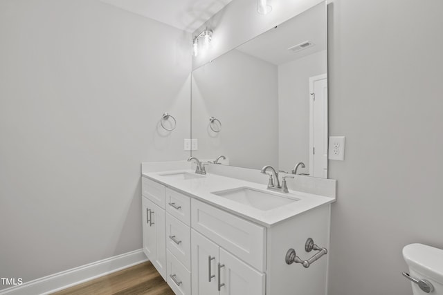 full bathroom featuring a sink, baseboards, toilet, and double vanity