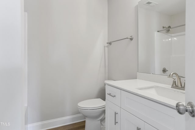 bathroom with vanity, wood finished floors, baseboards, visible vents, and toilet