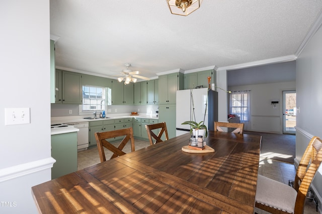 tiled dining area with ceiling fan, sink, a textured ceiling, and ornamental molding